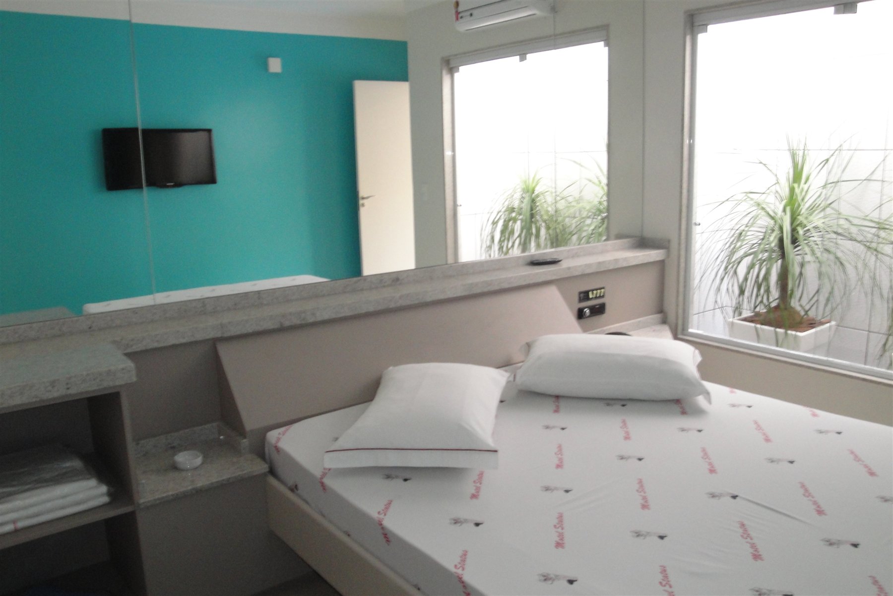 Suíte Super Luxo com cama de casal e parede em tom turquesa