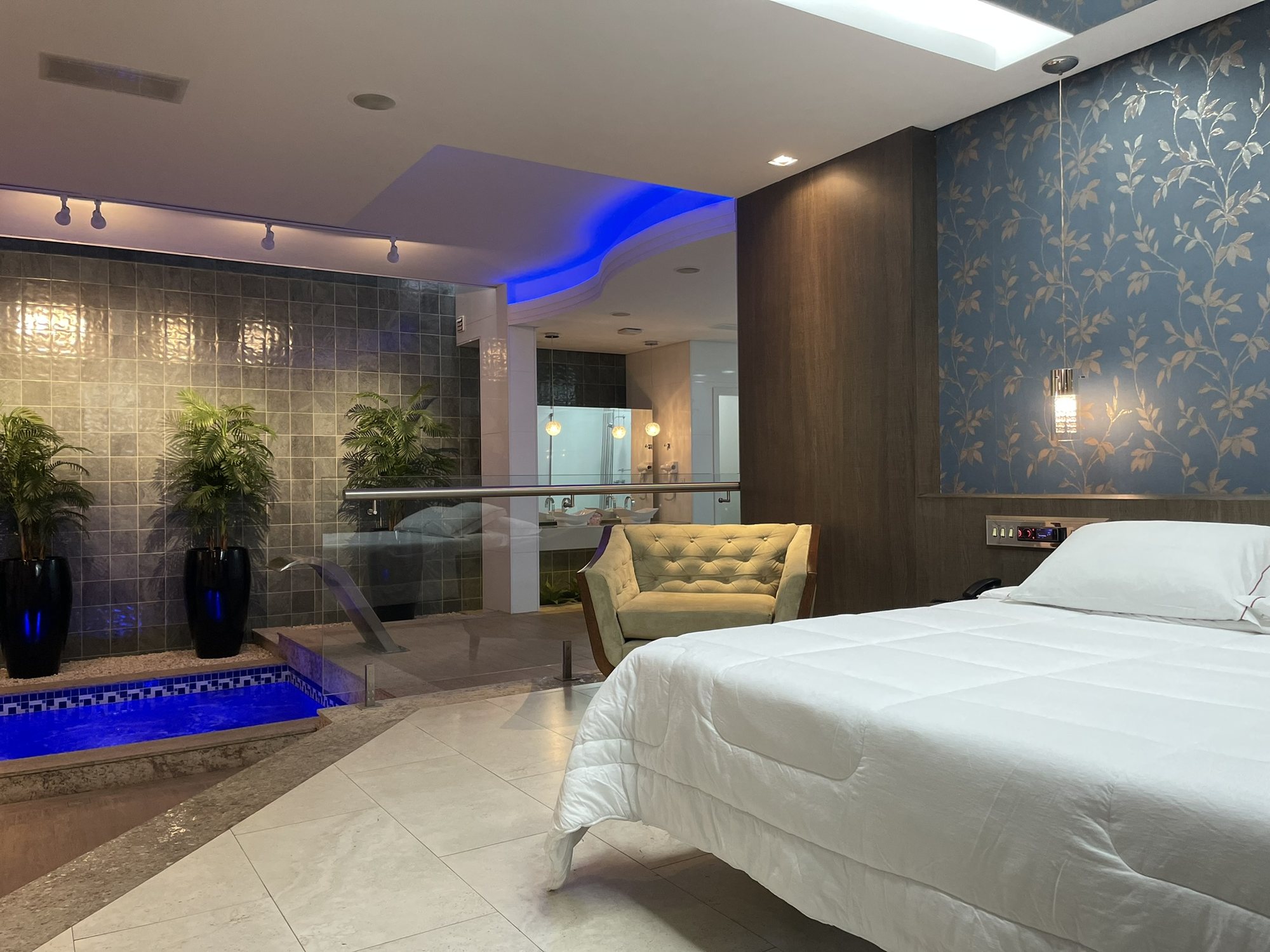 Quarto com poltrona, jardim e acesso à piscina