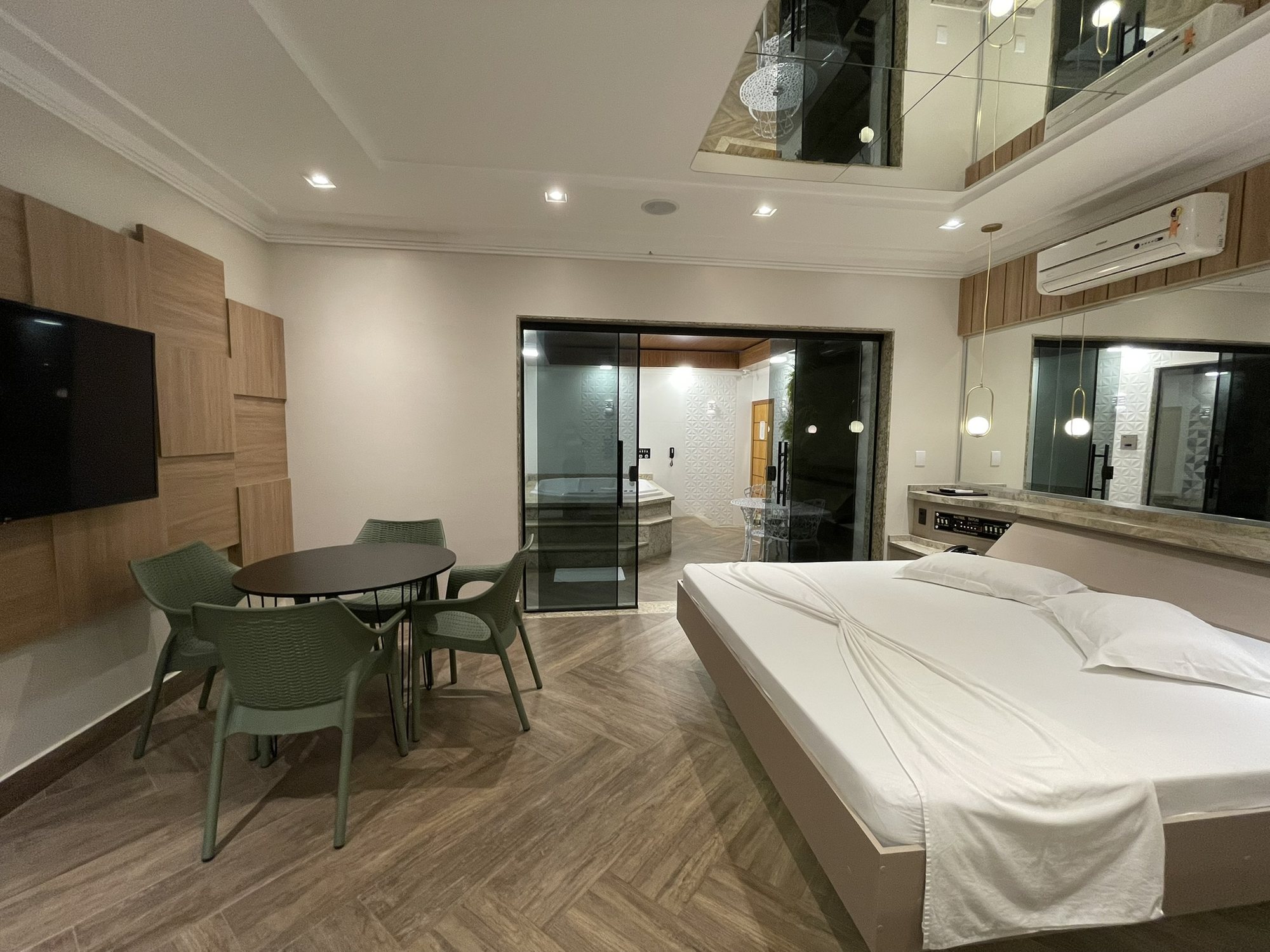 Quarto com Smart TV, mesa para refeições e acesso à área da hidro